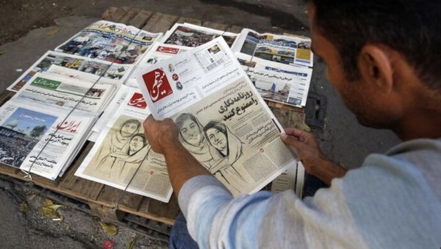 Man looks at newspaper with drawing of arrested journalists Elaheh Mohammadi and Niloufar Hamedi on  30 November 2022