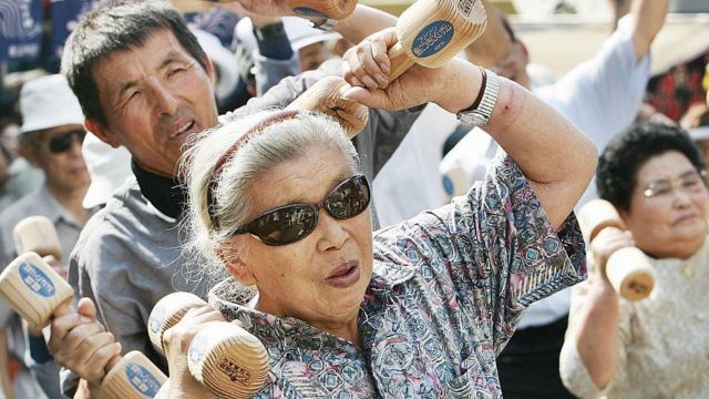 Personas mayores haciendo gimnasia al aire libre con pesas de madera