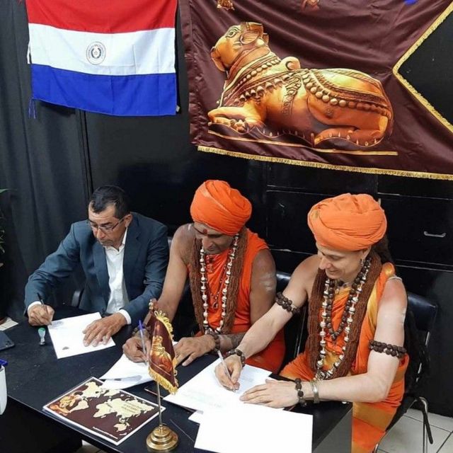 Representantes de Kailasa y uno del municipio de María Antonia, Paraguay, firmando acuerdos.