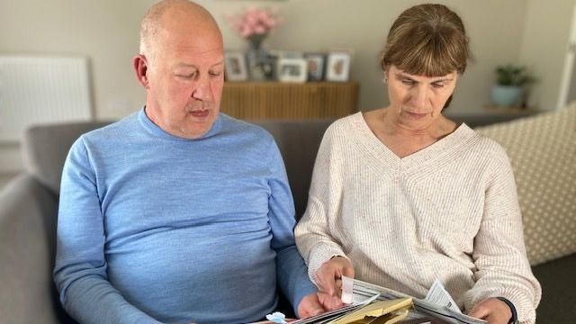 Terry Mott and his wife Moira reading hospital letters on the sofa at home