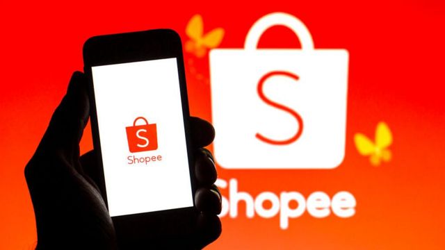 Mão segurando celular com logo da Shopee