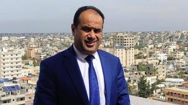 Dr Muhammad Abu Salamiya em pé em um telhado com Gaza atrás dele