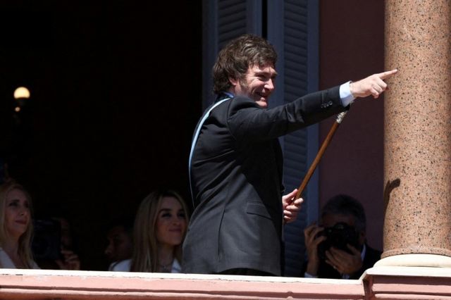 Javier Milei sorrindo e acenando para público da sacada de edifício