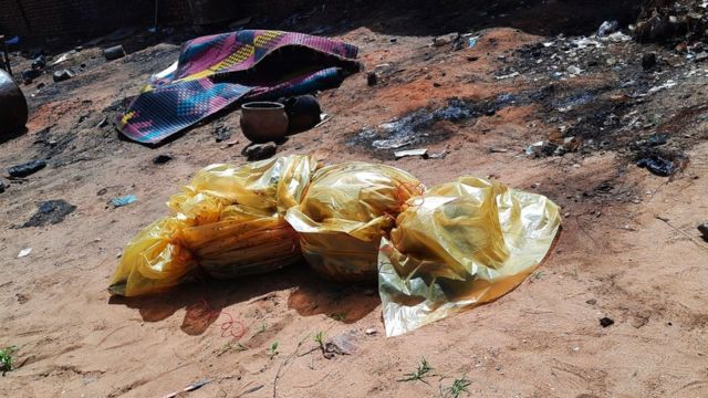 كيس بلاستيكي أصفر يلف جثة ويغطيها وسط الرمال والأنقاض. وشوهدت السجادات الملونة وبعض الأواني المصنوعة من الطين متناثرة على الأرض