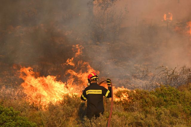 رجال الإطفاء يطفئون منزلا محترقا أثناء حريق هائل في جنوب شرق أتيكا في لاغونيسي، اليونان في 17 يوليو/ تموز 2023.