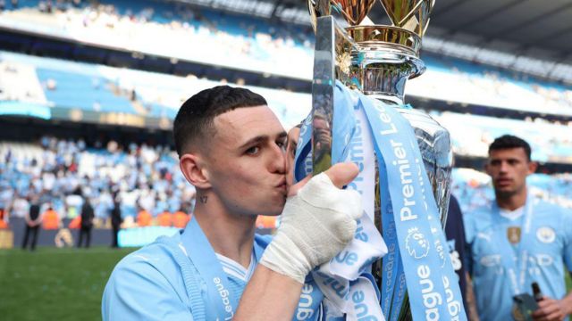 Phil Foden of Manchester City poses with the Premier League trophy after the Premier League match between Manchester City and West Ham United at Etihad Stadium