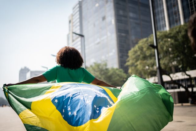Brasileira andando e segurando uma bandeira brasileira
