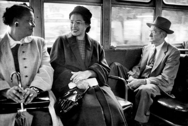 Rosa Parks (centro) andando de ônibus após fim da segregação