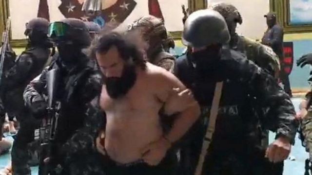 Homem barbudo é conduzido por policiais armados