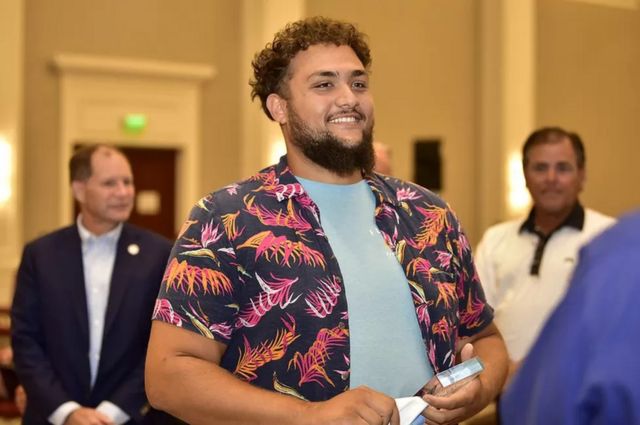 O professor de ciências surdo Brandon Call pegou a maior cobra de 2021. Na foto, ele usa uma camisa florida. É um homem jovem com barba e cabelos marrons e pele morena