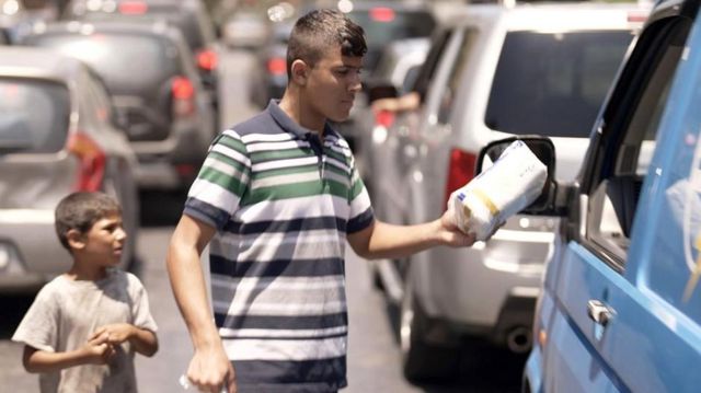 Muhammad sells tissues to passing cars in Lebanon