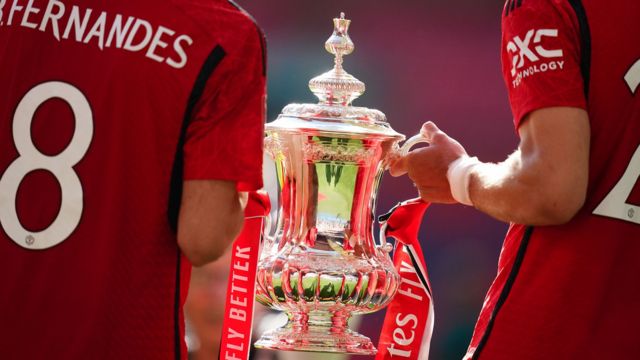 A backshot of Bruno Fernandes and Diogo Dalot holding the FA Cup