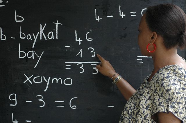 Une femme face au tableau dans une classe