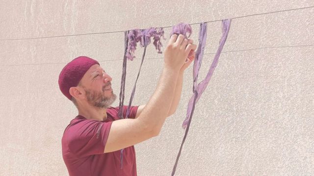 homem manuseando pano com tinta roxa