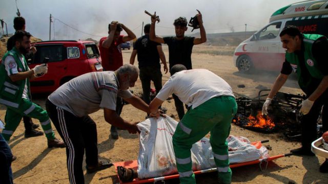 Paramédicos transportam os corpos de dois jovens palestinos cuja motocicleta foi atacada perto da cerca da fronteira entre a Faixa de Gaza e Israel 