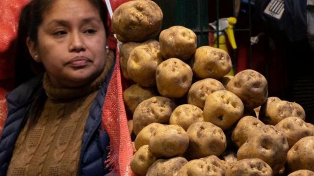 Mulher peruana junto a saco de batatas