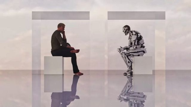 A man sitting while listening to a humanoid robot talking