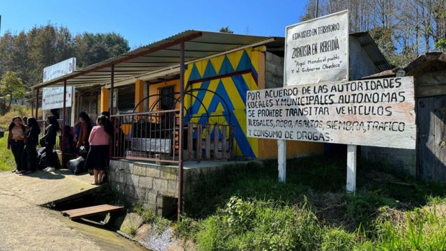 Unas niñas esperan el bus en las puertas Oventic.