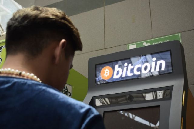 Pessoa em frente a um caixa automático de bitcoin