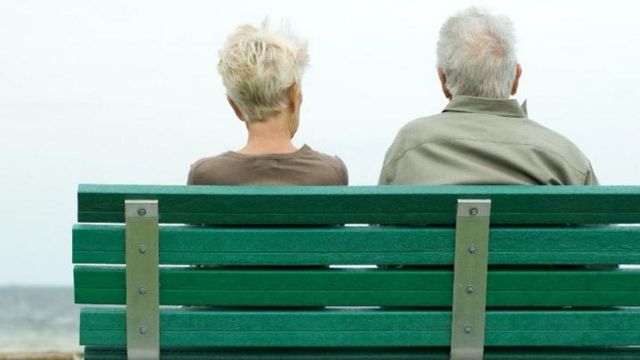 Casal de idosos de costas sentado em banco