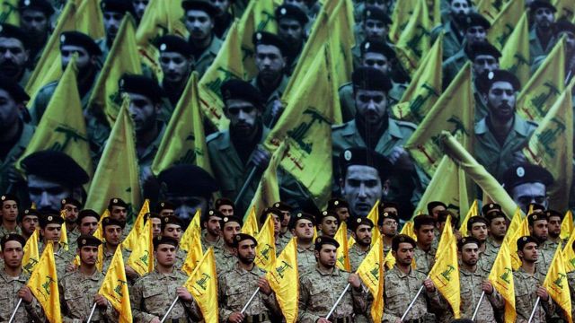 Ellerinde örgüt bayrakları bulunan, geçit törenindeki Hizbullah üyeleri 