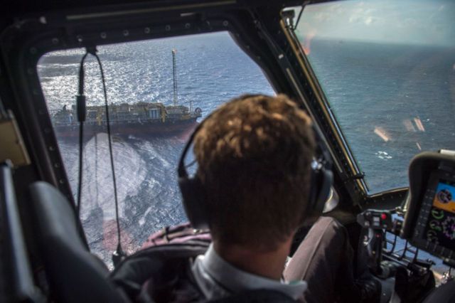 Piloto de helicóptero observa plataforma de exploração no mar