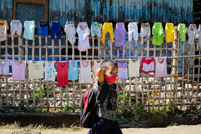 Um menino caminhando de máscara para a escola na ilha Diit