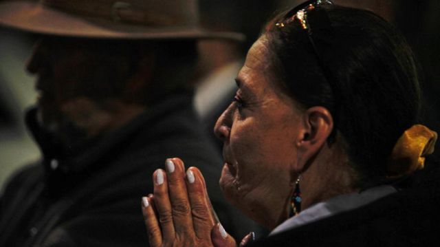 Una mujer contiene el llanto y une sus manos fuera del hospital donde trasladaron a Villavicencio