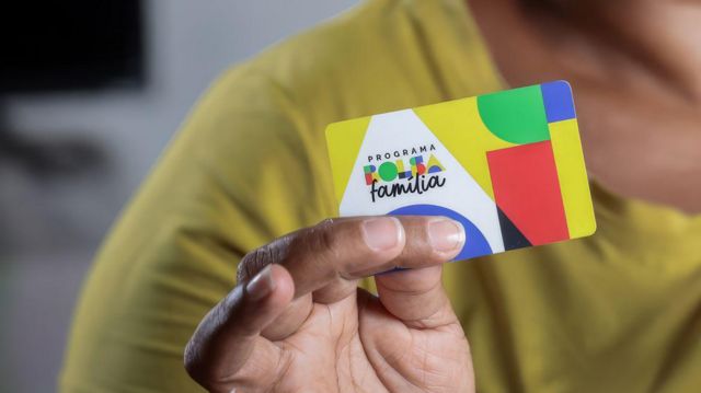 Mão feminina segurando um cartão do programa Bolsa Família 
