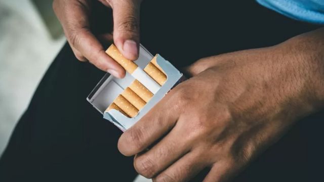 A person pulls a cigarette from a pack 