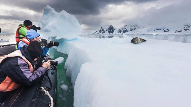 Turistas tomando fotos desde un bote inflable