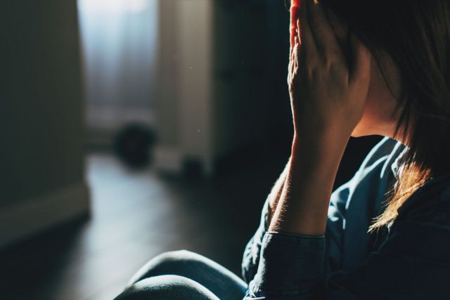 Una mujer llorando en un rincón de la casa