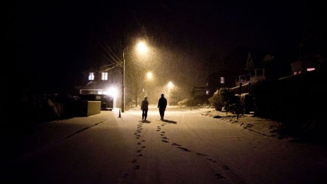 Dos personas caminando en la nieve por una ciudad