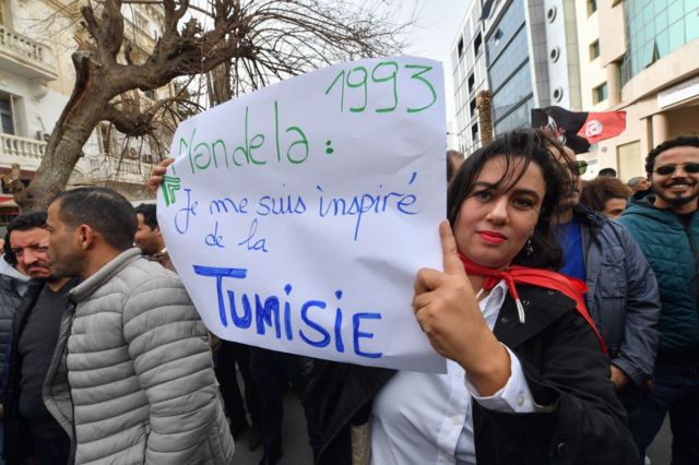 Des manifestants soulèvent des pancartes lors d'une manifestation à Tunis le 25 février 2023