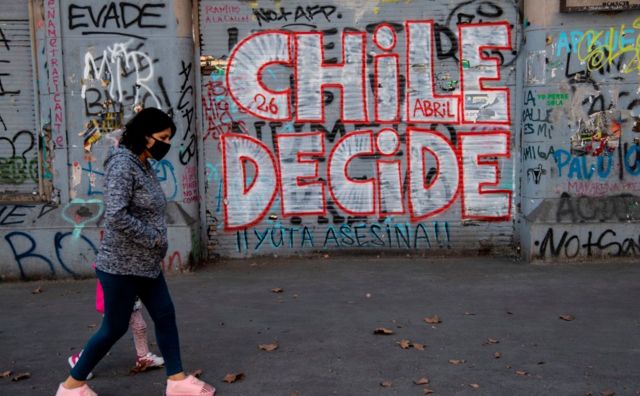 Mulher passa por uma pichação onde se lê "Chile Decide" em referência ao referendo de 25 de outubro para mudar a constituição da era da ditadura militar do Chile