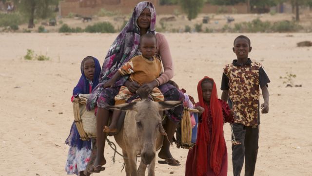 A woman and her family ride on a donkey