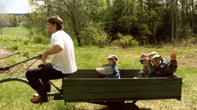 Pai com dois filhos na carroça