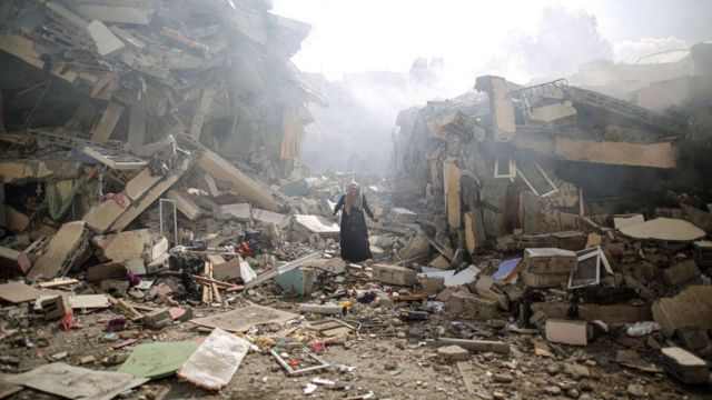 Triste, uma moradora caminha entre os escombros do bairro de al-Zahra depois do bombardeio