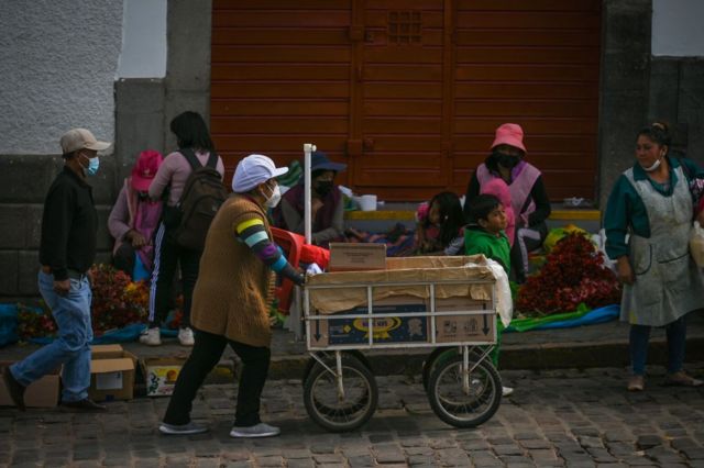 Una mujer empuja un carro en un mercado de Cusco.