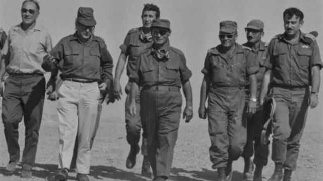 Moshe Dayan caminhando ao lado de militares israelenses