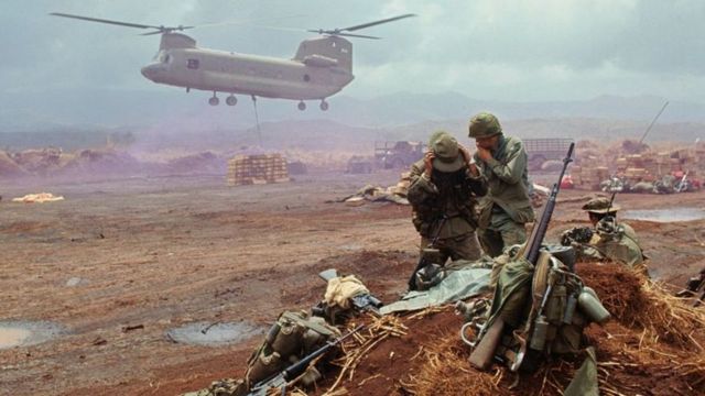 Scène de guerre en présence d'un hélicopère miliaire et de trois soldats