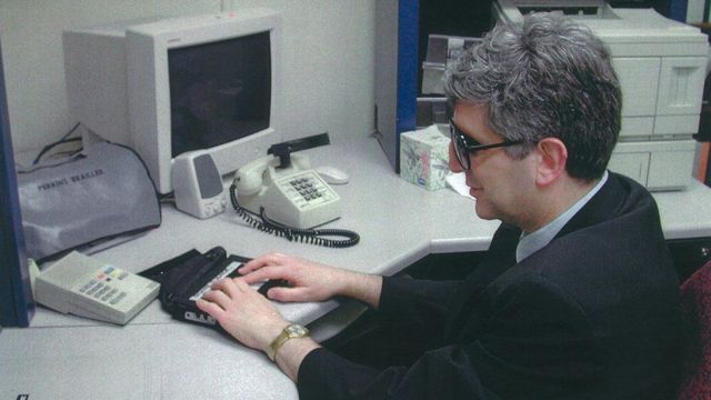 Alan Clive em uma mesa usando terminal braille