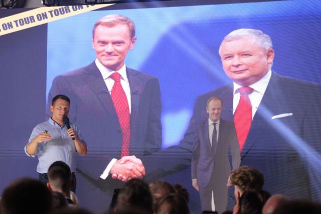 Один із лідерів "Конфедерації" Славомир Менцен на тлі зображення Ярослава Качинського (справа) з Дональдом Туском на передвиборчому мітингу 16 вересня 2023 року в Щецині, Польща