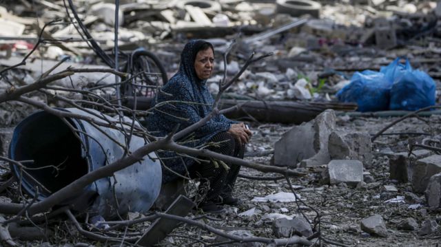 امرأة فلسطينية تجلس بين الأنقاض في حي الرمال المدمر بعد غارة جوية إسرائيلية على مدينة غزة، 10 أكتوبر/تشرين الأول 2023.