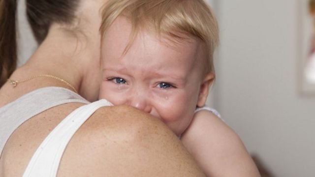 Bebê chorando no colo da mãe