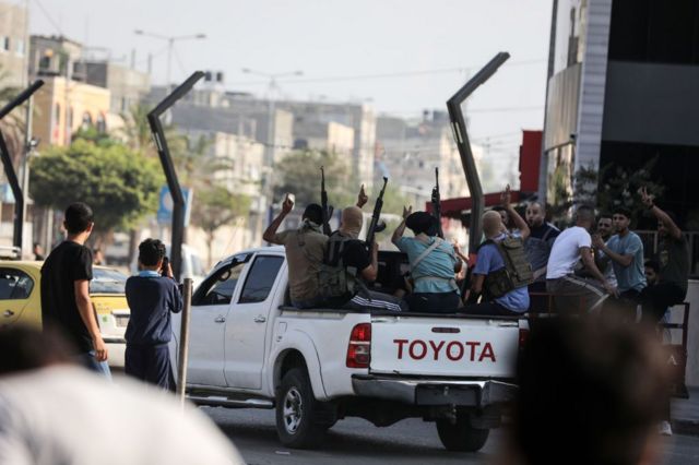 Hammas fighters returning to Gaza in a pick-up truck with guns pointed in the air