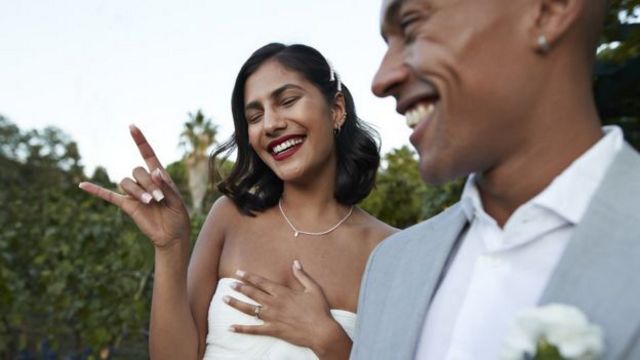 Casal heterossexual sorrindo com vestimentas de casamento