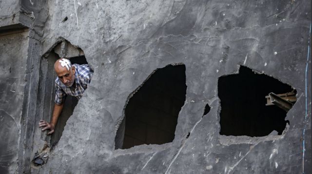 رجل مصاب يتفقد الأضرار التي لحقت بكنيسة القديس برفيريوس للروم الأرثوذكس بعد غارة جوية ليلية في غزة
