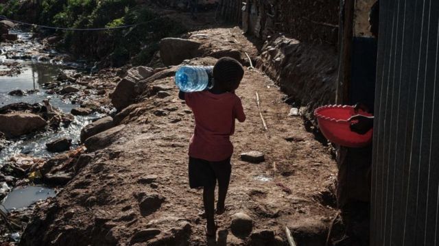 Seorang anak membawa botol air setelah mengisinya di kios air bersih yang dipasang oleh LSM Lokal Cemerlang Harapan untuk Masyarakat (SHOFCO) di permukiman kumuh Kibera, Nairobi, pada 20 Maret 2020.