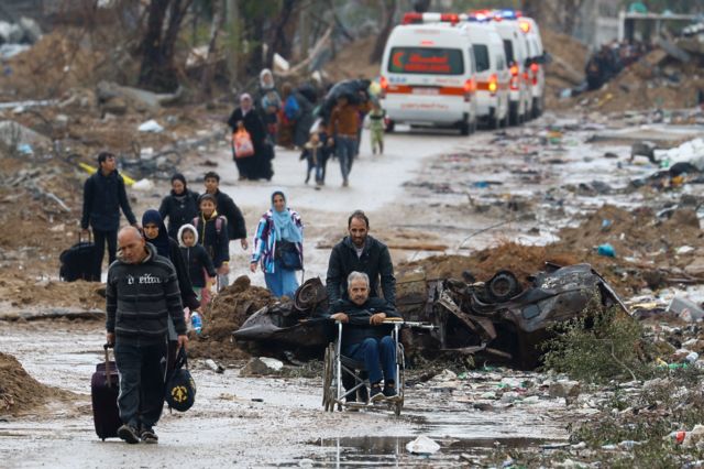 Pessoas caminhando em Gaza, incluindo um homem cadeirante